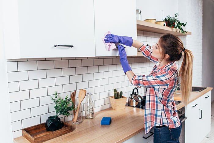 woman cleaning cabinet in kitchen